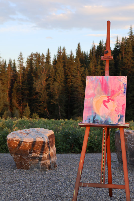 “Heart Without a Map” – original abstract acrylic painting by Olia Nychyporenko (artbyOliaN), displayed on an easel outdoors. Soft pinks, crimson, and coral hues flow across the canvas in an emotive, textured composition.