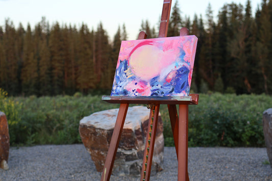 “My Frequency” – original abstract acrylic painting by Olia Nychyporenko (artbyOliaN), shown outdoors on an easel with forest backdrop. Textured, expressive work in pink, blue, and lavender tones.